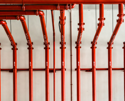 Front view of red color metal pipe on white wall