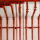 Front view of red color metal pipe on white wall