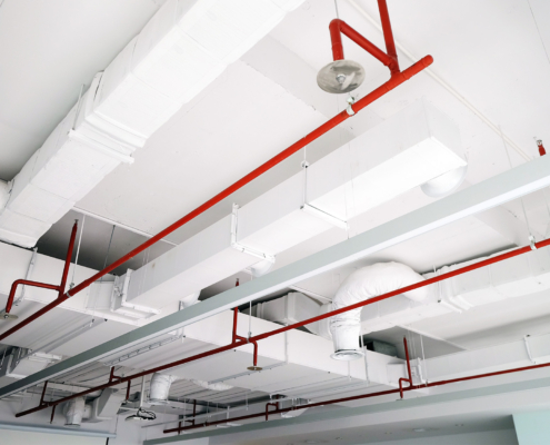 Perspective view of white air duct on the ceiling with red water sprinkler pipe