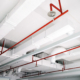 Perspective view of white air duct on the ceiling with red water sprinkler pipe